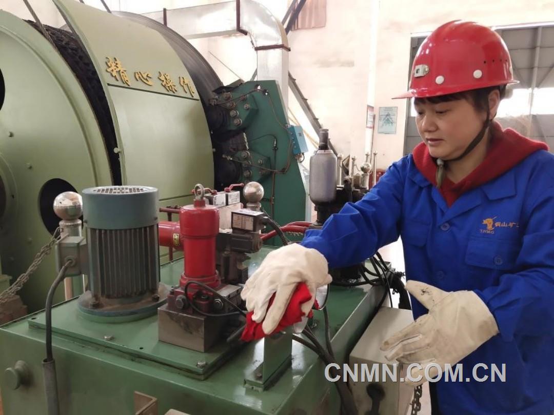 1.1卷扬女工张早霞在工作间隙为设备进行除尘保养