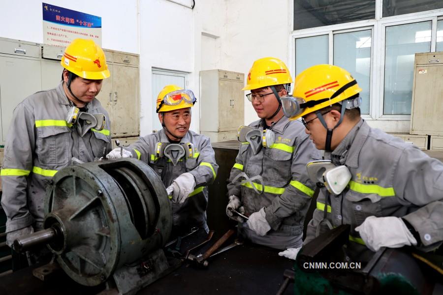 图为张文华在保全车间维修间指导青年员工理解电磁离合器工作原理及维修要点